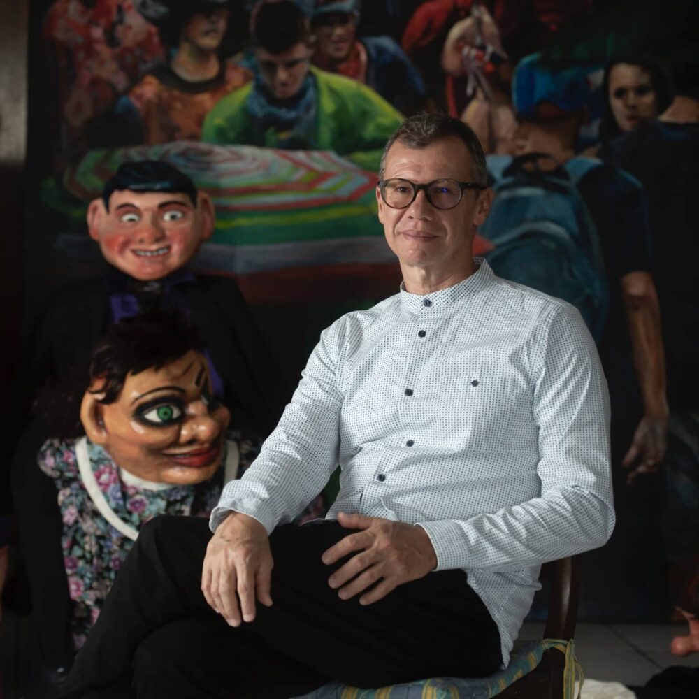Adrian Arguedas in his studio surrounded by masquerade paintings and masked puppets