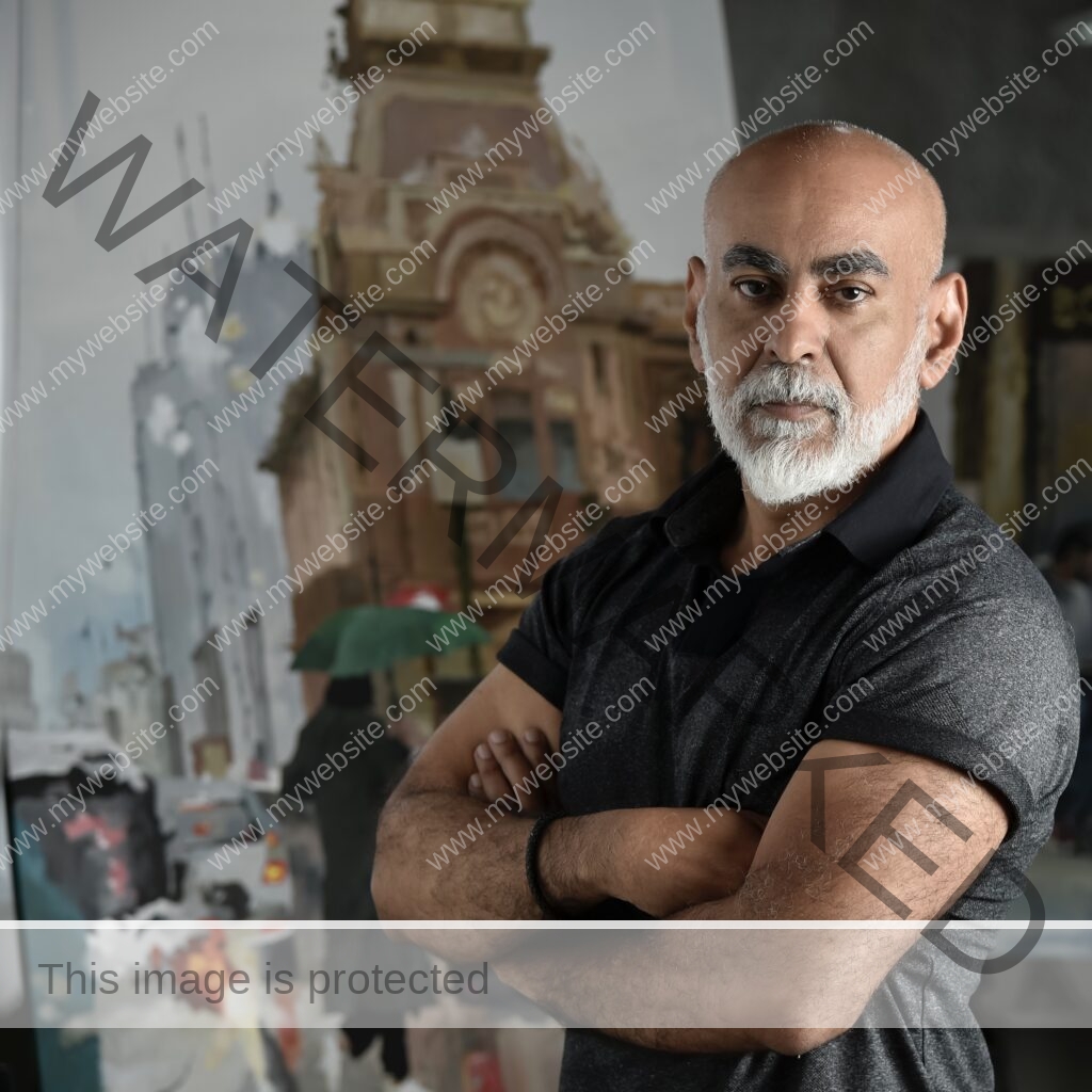 Portrait of Osvaldo Sequeira in his studio, 2023. Abstract impressionist figurative painting in the background.