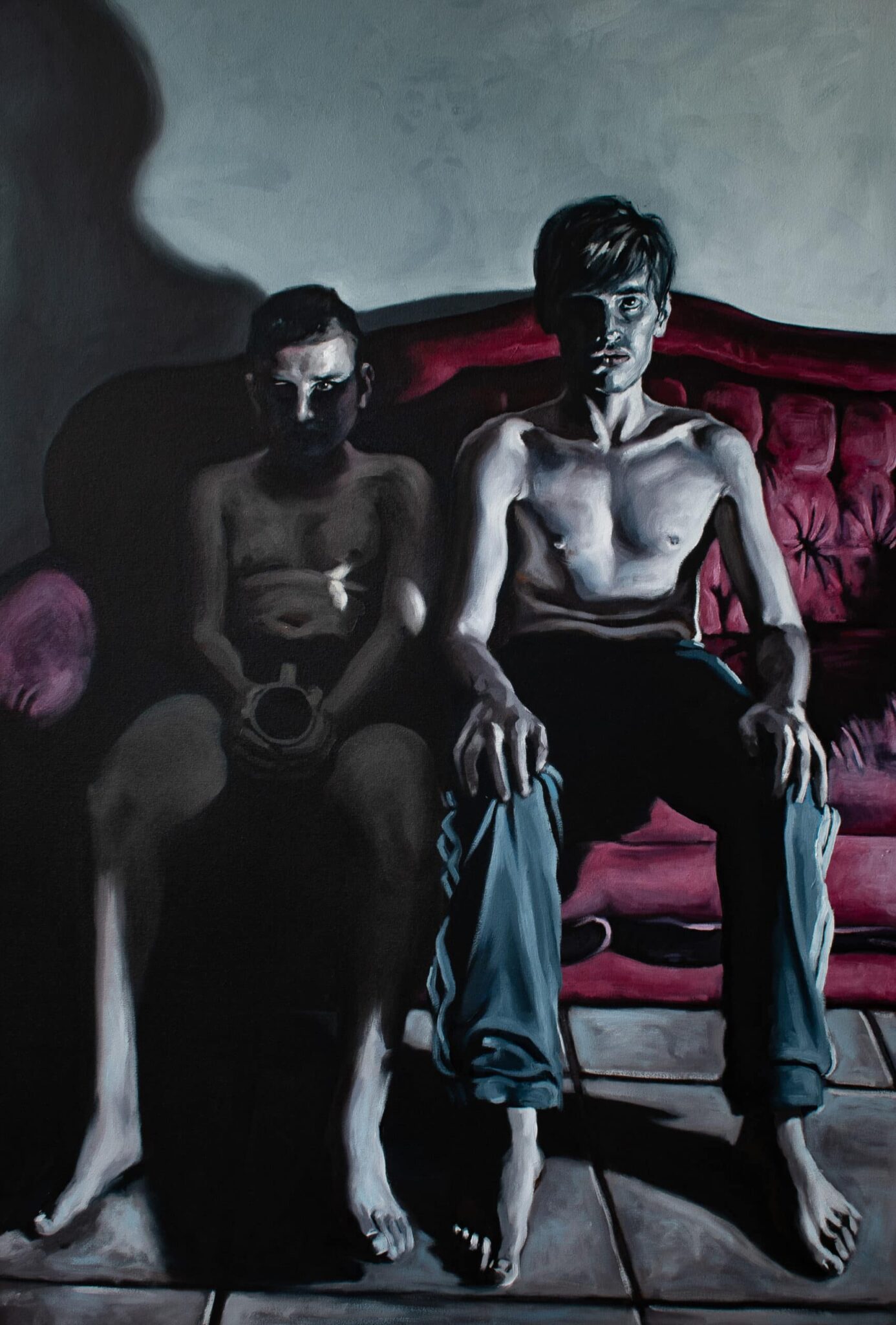 Two shirtless men on a red couch: one, shadowed and contemplative with mug; the other, illuminated in blue pants, bathed in dramatic light. , an original work available at MÍRAME Fine Art.