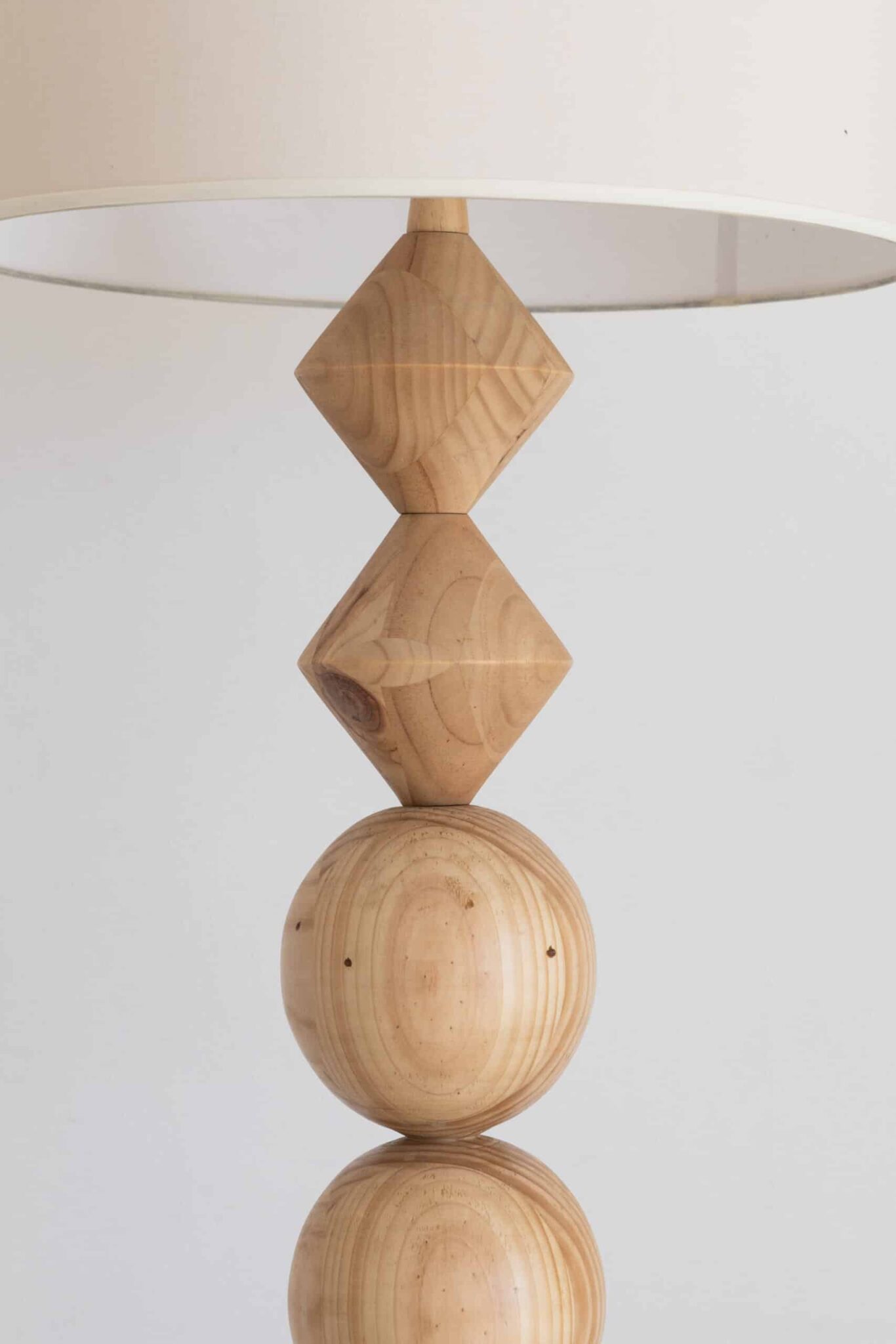 The Olimpia lamp’s base elegantly blends Art Deco motifs—a wooden sphere and diamonds—topped with a pristine white shade. , an original work available at MÍRAME Fine Art.