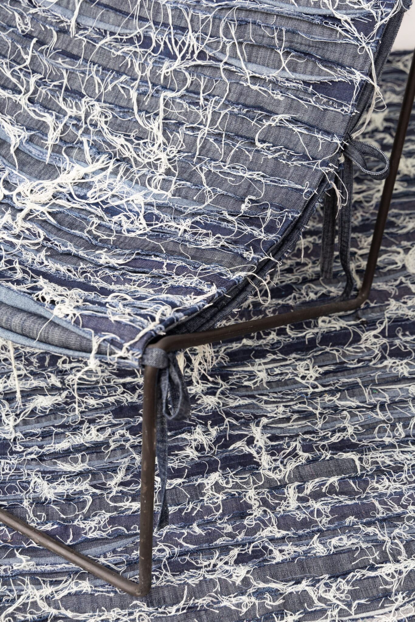 The Olimpia chair’s metal frame and shredded blue denim upholstery echo the rug, as an art deco vase lends sophistication to this modern tableau. , an original work available at MÍRAME Fine Art.