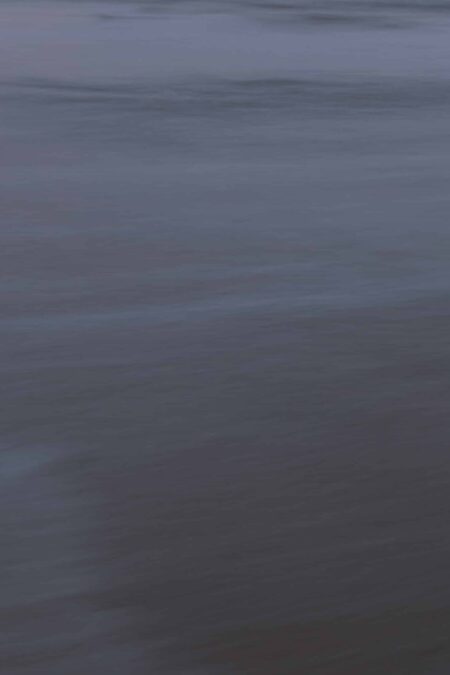 Costa Rican ocean photography by Juan Tribaldos, featuring a moody close-up of an ocean surface. Deep blues and greys evoke a moody atmosphere.