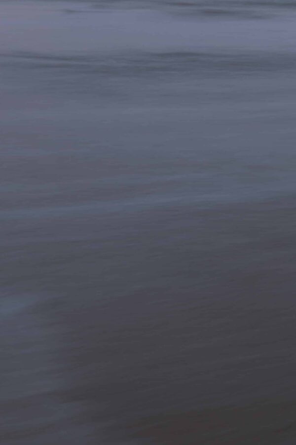 Costa Rican ocean photography by Juan Tribaldos, featuring a moody close-up of an ocean surface. Deep blues and greys evoke a moody atmosphere.