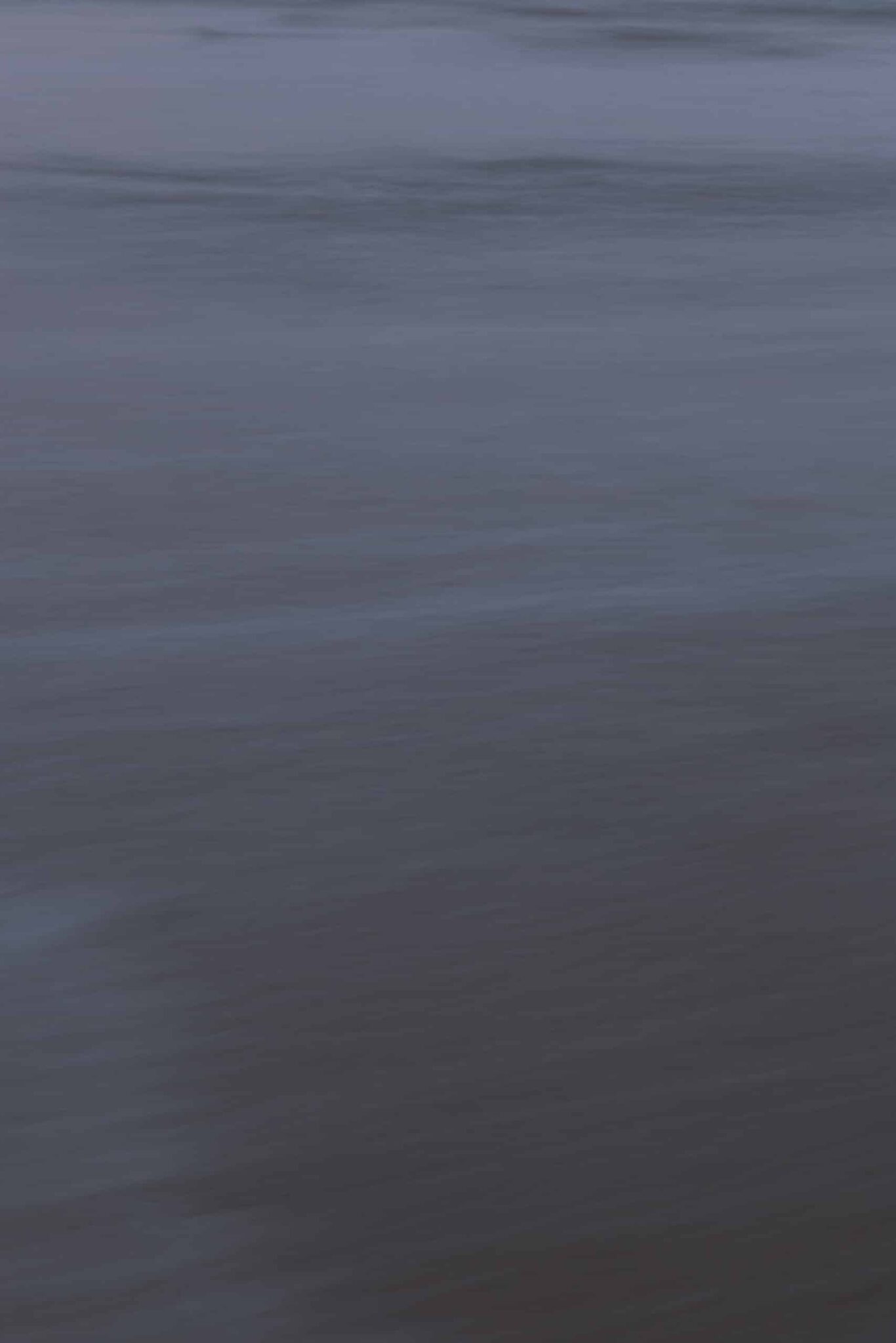 Costa Rican ocean photography by Juan Tribaldos, featuring a moody close-up of an ocean surface. Deep blues and greys evoke a moody atmosphere.