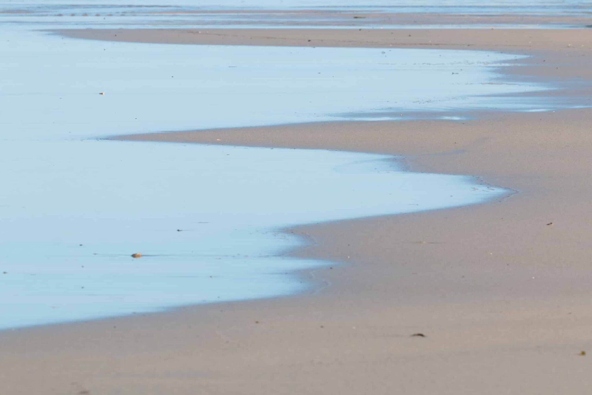 Beach and Ocean photography by Leonardo Ureña. This tranquil image features silvery blue water lapping onto sand.