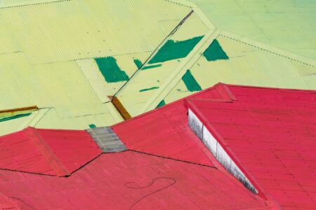 Geometric urban photograph featuring red and yellow rooftops with geometric forms. By Leonardo Ureña.