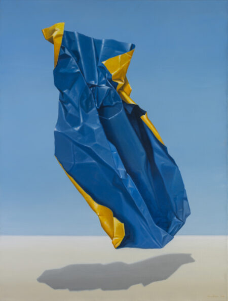 Hyperrealist painting of a floating blue and yellow piece of garbage against a block blue background and floating above a beige ground. This painting comments on the effects of consumer culture on our environment.