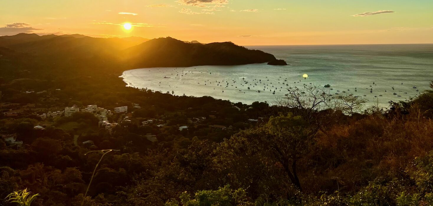 Sunset fading behind a mountain overlooking Playas del Coco bay. the image is used in an article about the Costa Rican economic growth and why so many people are investing in the country.