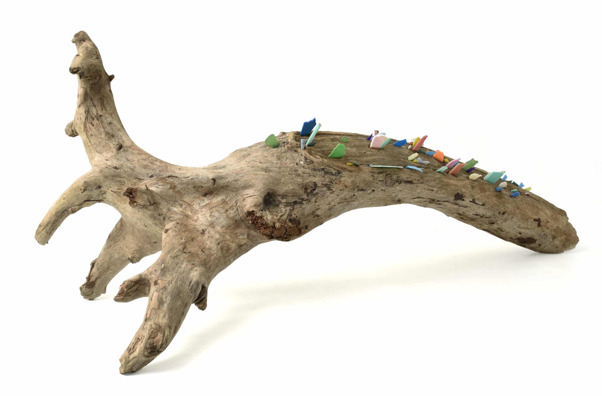 Presencias Incrustadas 001: A sculpted curved wooden trunk hosts an intricate village of vibrant miniature houses, trees, and fences. , an original work available at MÍRAME Fine Art.