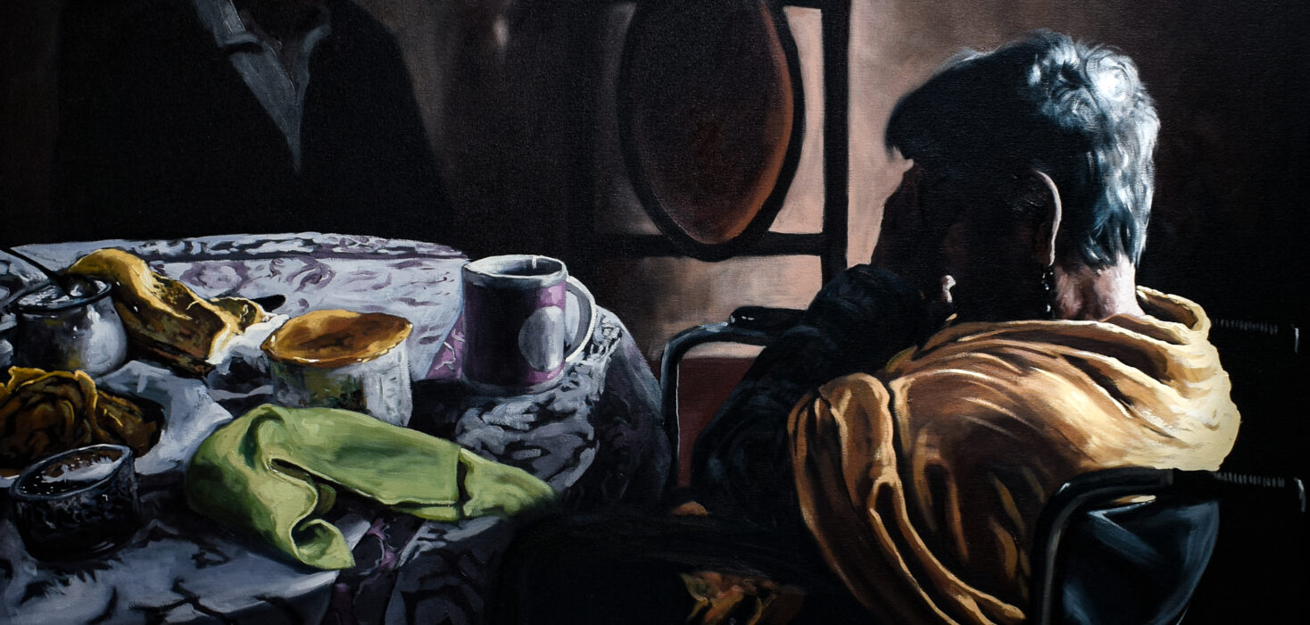 An emotive still life portraiture painting featured in a Jesus Mejia exhibition of a figure sitting at a table, a hand held to her head in grief. The still life scene creates a sense of loss and the striking contrasts of light and shadow create poignancy and increased sadness.