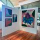 Andaz Art week. A display of bright abstract paintings on white walls.