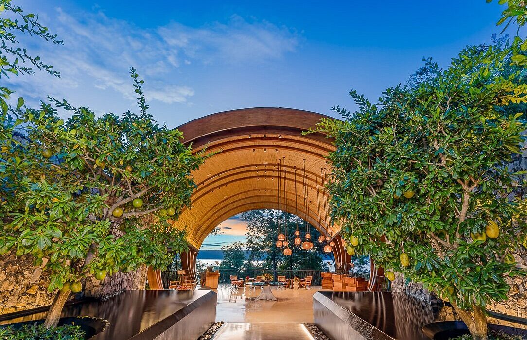 Image of a hotel entryway, looking down a walkway to tables and chairs and the ocean beyond. To advertise Andaz Art Week.