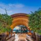 Image of a hotel entryway, looking down a walkway to tables and chairs and the ocean beyond. To advertise Andaz Art Week.