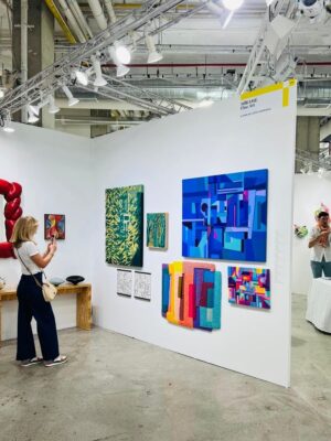 A woman taking photos of artwork on a white wall, Future Fair 2025