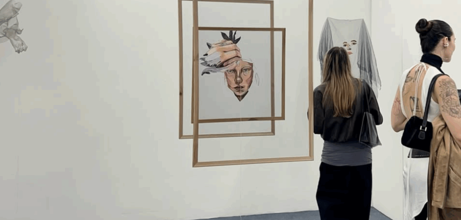 Exhibition view at salita_temporal in San José, featuring Elena Obando suspended portrait framed by layered wooden rectangles, with visitors observing works on the surrounding white walls.