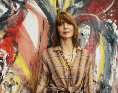 Portrait of a woman against a colourful abstract painting, representing a new exhibition in Mexico City for the artist Aimée Joaristi.