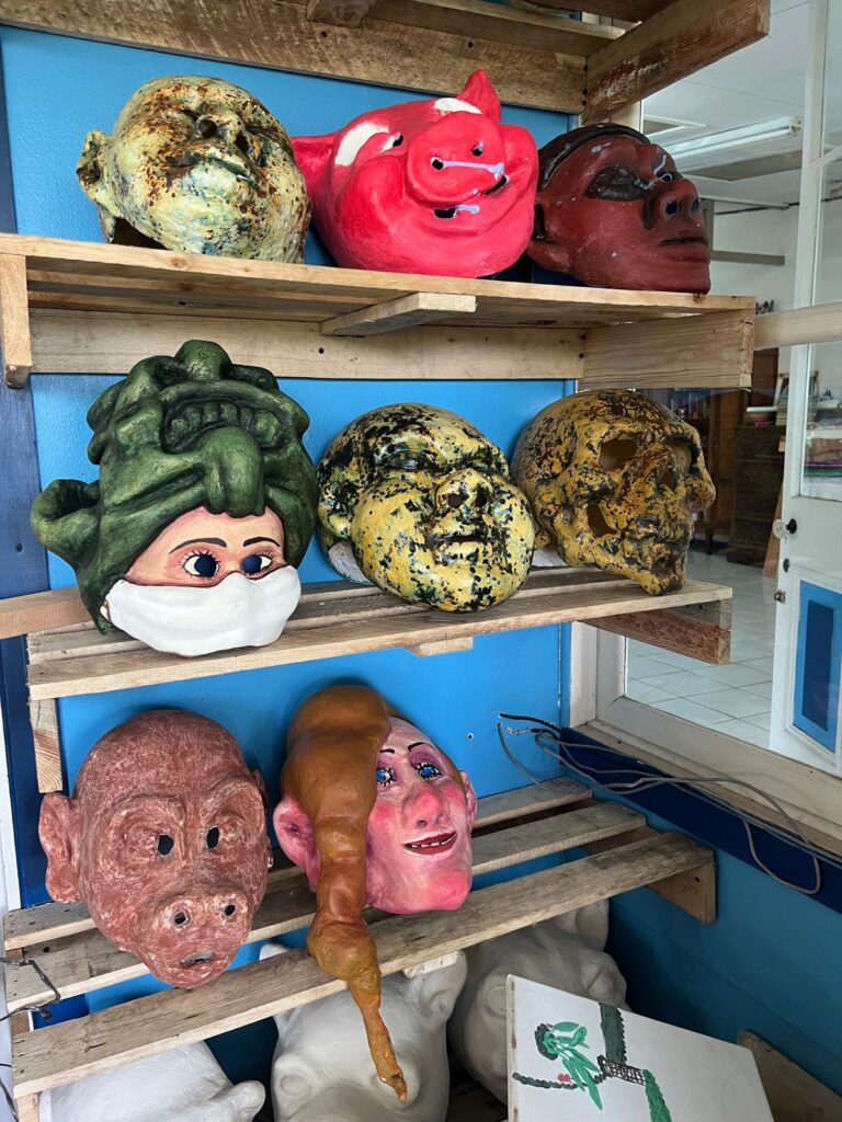 Different coloured masks sitting on a shelf in an artist studio