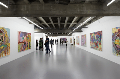 Within a luminous, spacious corridor of white walls and concrete ceiling, vibrant abstracts in San José independent art space. An original work available at MÍRAME Fine Art.