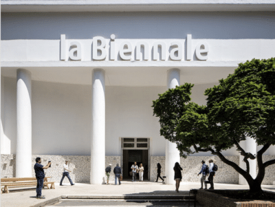 Visitors gather before a neoclassical building marked "Venice Biennale 2026," framed by verdant tree and serene reflecting pool. , an original work available at MÍRAME Fine Art.